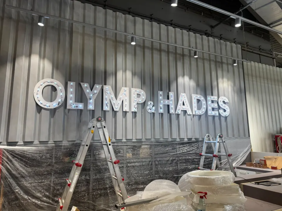 Leuchtbuchstaben „Olymp & Hades“ im KULT Store Flensburg – hinterleuchtete Einzelbuchstaben an der Wellblechwand im Verkaufsraum
