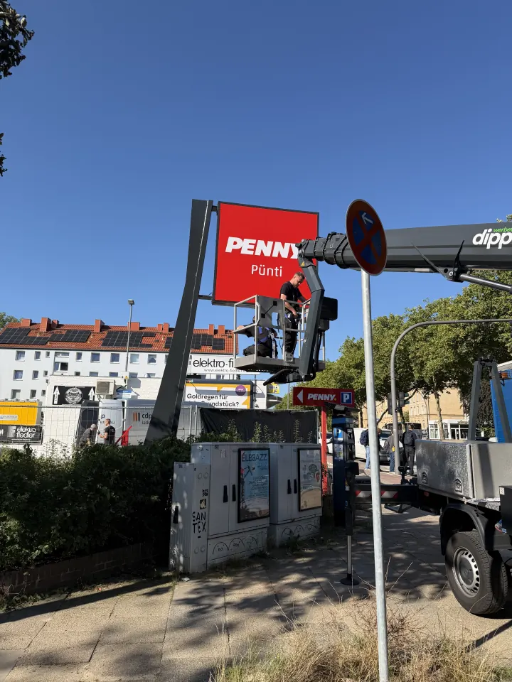 Leuchtkasten am Werbepylon für PENNY Pünti – Montage des beleuchteten Logos mit unserer Hubarbeitsbühne